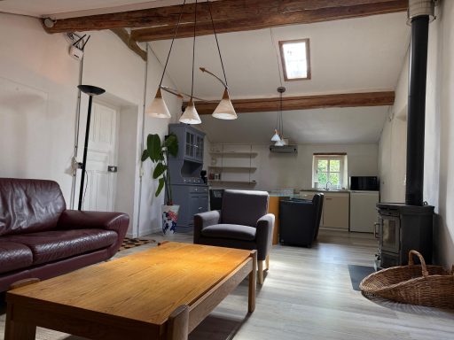 Gezellige woonkamer met comfortabele meubels, een houten tafel en een open keuken.